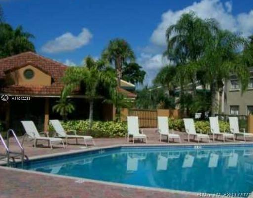 Outdoor swimming pool area with lounge chairs and surrounding buildings.