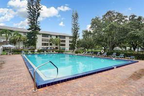 Outdoor swimming pool area with surrounding trees and sun loungers.