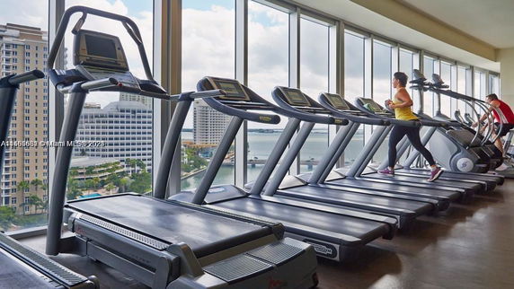 Gym area with treadmills and large windows showing an outdoor cityscape.
