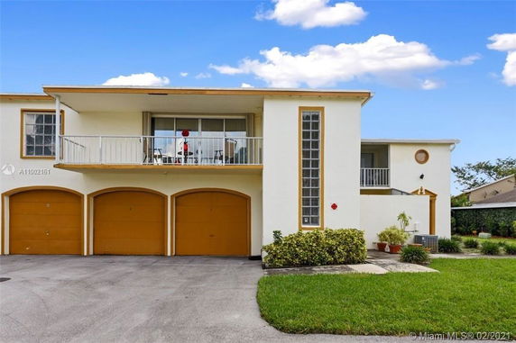 Front view of a two-story house with three garage doors and a balcony.