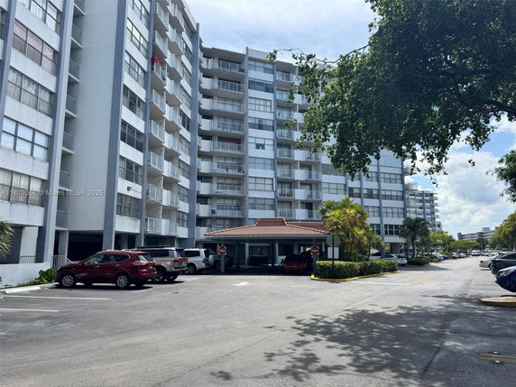 Front view of a multi-story apartment building with parking area.