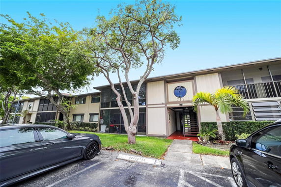 Front view of a two-story apartment building with reserved parking spaces.