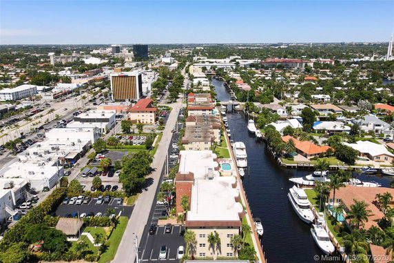 Wide-angle aerial view of a city showing buildings, roads, and a canal with boats.