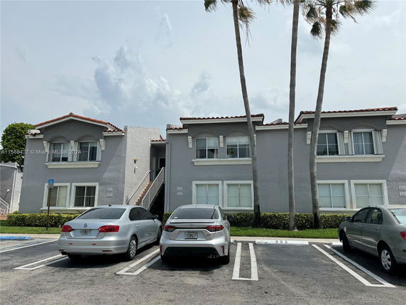 Front view of a multi-story residential building with attached parking spaces.