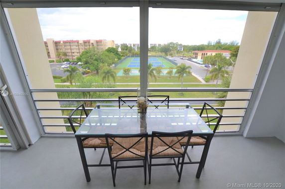 View from a balcony of a tennis court and surrounding buildings.