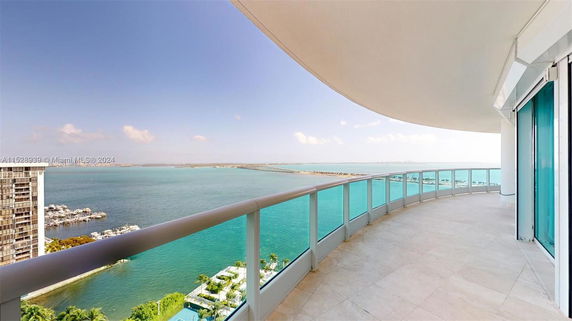Curved balcony with glass railings overlooking a body of water.