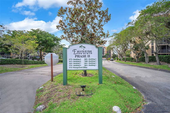 Entrance sign for Environ Phase II with surrounding buildings and trees.