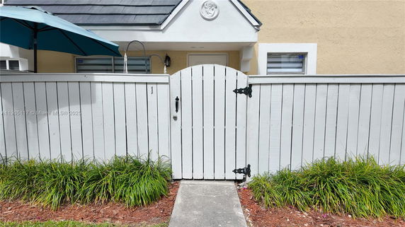 Front view of a house with a white wooden fence and gate.