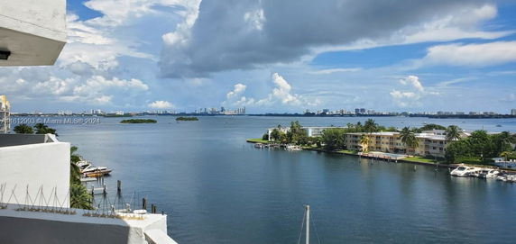 Wide angle view of a coastal area with buildings, boats, and water.