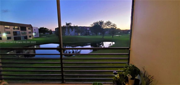 Panoramic view of surrounding buildings and greenery from a balcony with a railing.