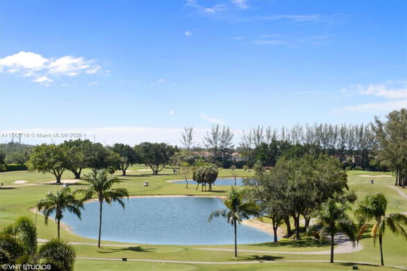 Panoramic landscape view of a golf course with a lake and trees.