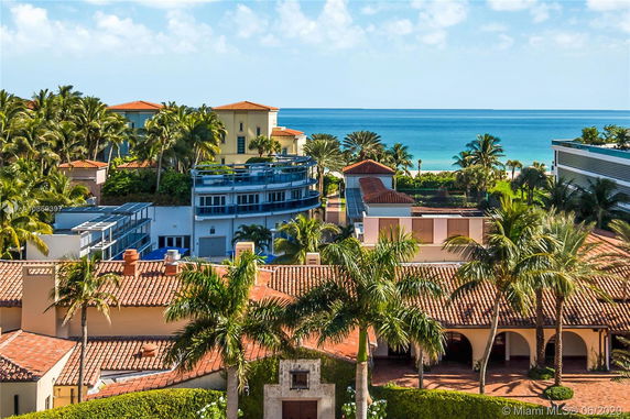 Rooftop view of multiple buildings with red tiled roofs near the coastline.