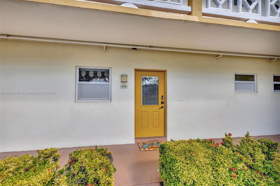 Front view of a building entrance with a yellow door and adjacent windows.