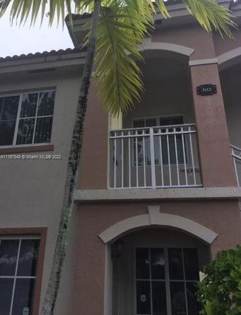 Front view of a two-story house with a small balcony and arched entrance.