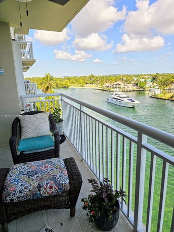 View of waterway from a balcony with wicker furniture and plant pots.