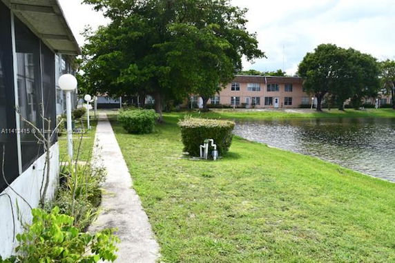 View of apartment buildings near a lake with a walkway and trees.