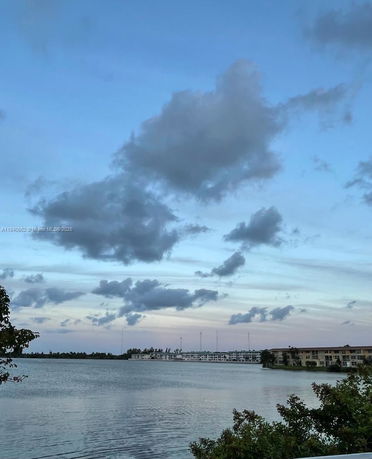 Panoramic view of a lake with buildings in the distance under a cloudy sky.