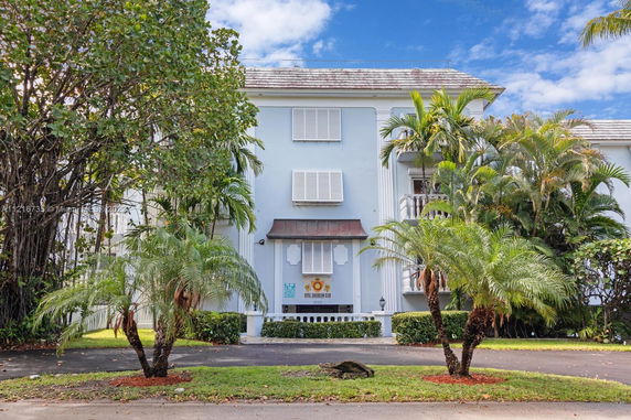 Front view of a multi-story building with balconies and shutters.