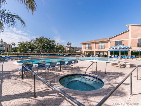 Outdoor swimming pool area with lounge chairs and umbrellas.