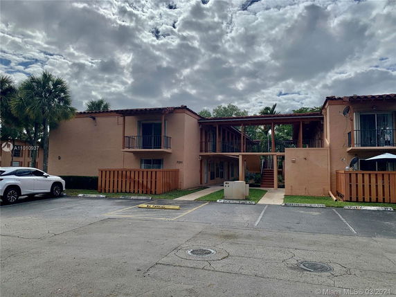 Front view of a two-story residential building with balconies and parking area.