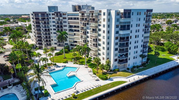View of a multi-story residential building with a large swimming pool in front.