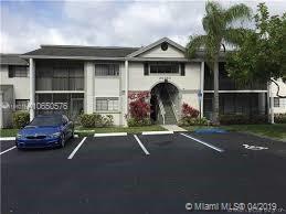 Front view of a two-story apartment building with a parking area in front.