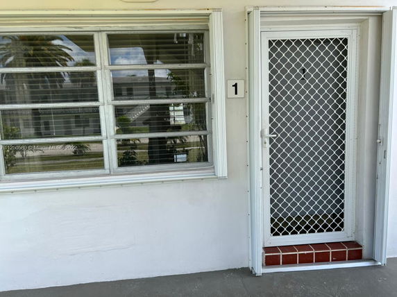 Front view of a house entrance with a screen door and large window.
