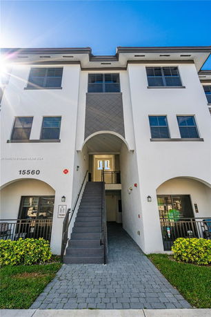 Front view of a multi-story building with exterior stairs and multiple windows.