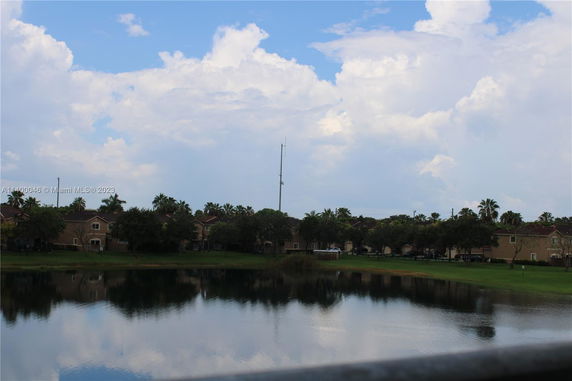 View of houses and trees with a lake in the foreground.