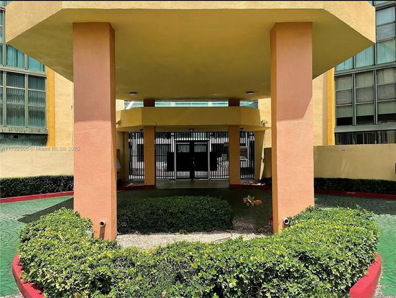 Front view of a building entrance with columns and gated entry.