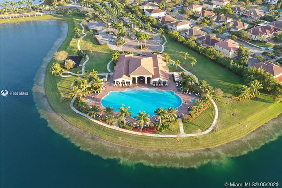 Aerial view of a clubhouse with a large swimming pool and surrounding landscaped area.