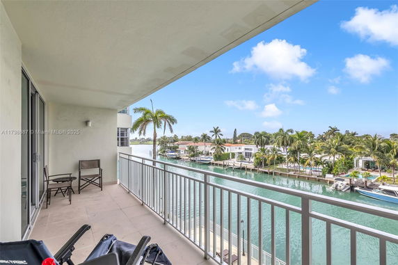 Balcony view overlooking waterway and houses with palm trees.