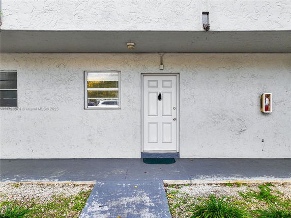 Front view of a building entrance with a white door and small windows.