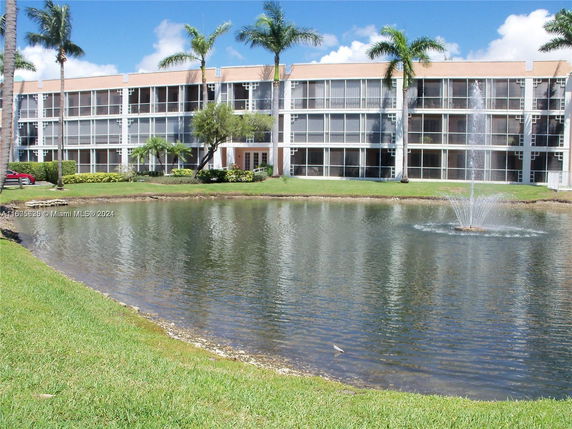 Front view of a three-story building with a pond and fountain.