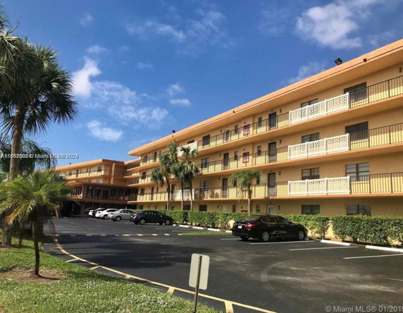 Front view of a multi-story residential building with balconies and parking area.