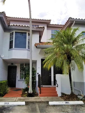 Front view of a townhouse with a tiled roof and palm tree.