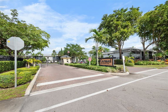Entrance view of a gated residential community with a security gate and sign.