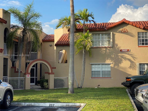Front view of a two-story building with red-tiled roof and arched entrance.
