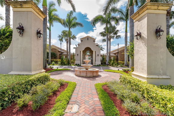 Front view of a building with a central entrance and a courtyard fountain, surrounded by palm trees.