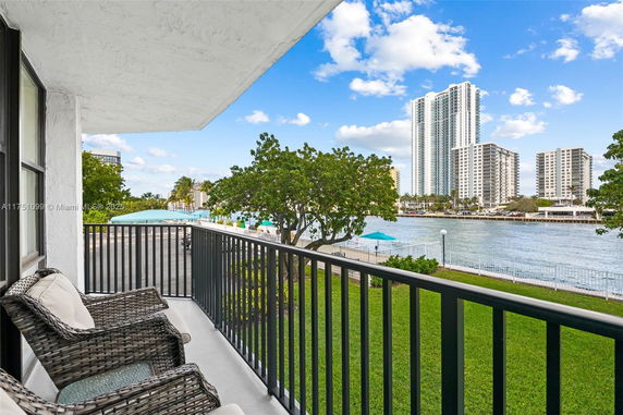 View from a balcony overlooking a waterfront area with high-rise buildings in the distance.