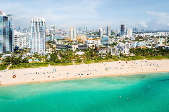 Panoramic view of a beach with high-rise buildings and city skyline in the background.