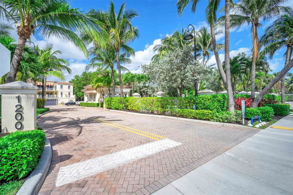 Entrance area with palm trees and a view of surrounding residential buildings.