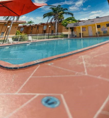 Outdoor swimming pool area with chairs and umbrellas.