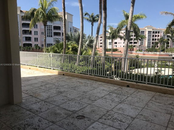 View from a balcony overlooking a multi-story residential building with palm trees.