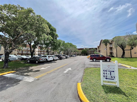 Outdoor parking area with several parked cars and adjacent residential buildings.