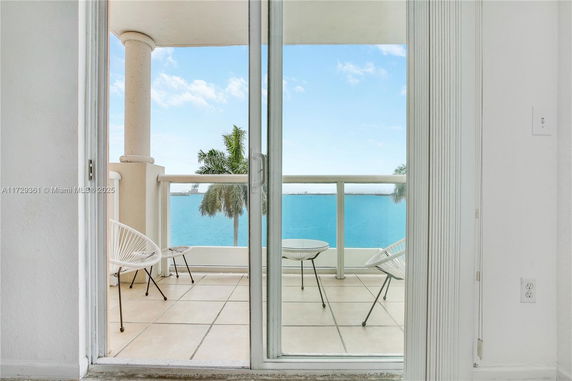 View from a balcony showing a water body and palm trees.