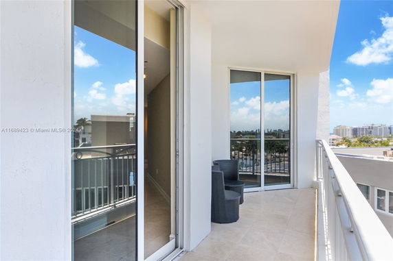 Balcony area with glass doors and railings overlooking city buildings.