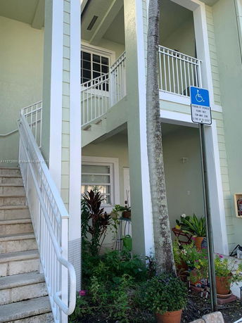 Front view of a two-story building with stairs and a balcony.