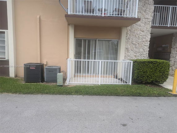 Front view of a residential building with a small balcony and air conditioning units.