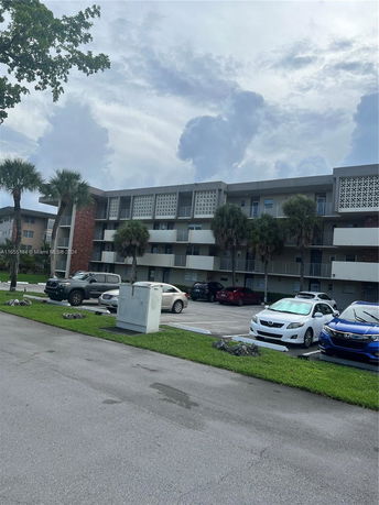 Front view of a multi-story residential building with a parking area in front.